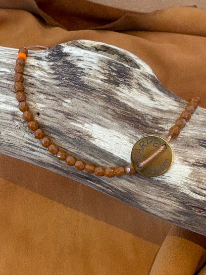 Détail du médaillon Carpe Diem sur bracelet brun beige
